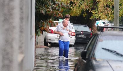 Un hombre sostiene a un niño mientras camina por una calle inundada, miércoles 3 de abril de 2013, en La Plata (Argentina).