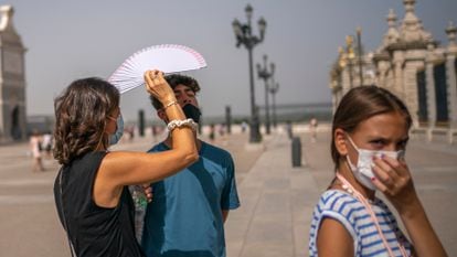 Una mujer protege del sol con un abanico a un joven en Madrid, este miércoles.