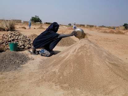 Ouedraogo Rasmata, quien huyó de los ataques de militantes armados en la región del Sahel de Soum, prepara la arena para venderla a los trabajadores de la construcción en un campamento informal para personas desplazadas en las afueras de Ouagadougou, Burkina Faso, el 19 de noviembre de 2020.