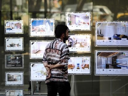 Un joven mira anuncios de una inmobiliaria en Barcelona.