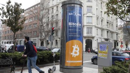 Un joven pasa junto a un panel de publicidad de bitcóin en Madrid