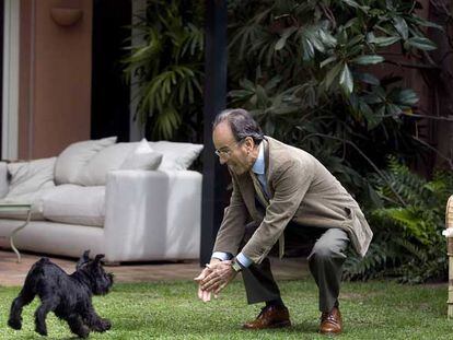 Santiago Dexeus juega con<i> Chunga,</i> su perra, en el jardín de su casa.
