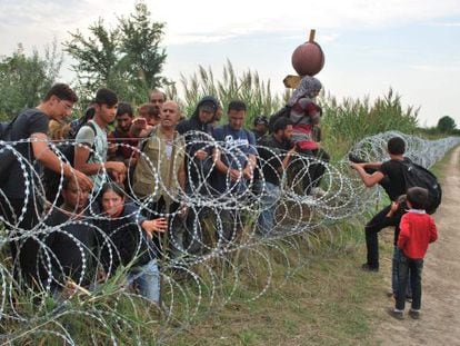 Varios refugiados sirios intentan saltar la alambrada de la frontera entre Hungr&iacute;a y Serbia.