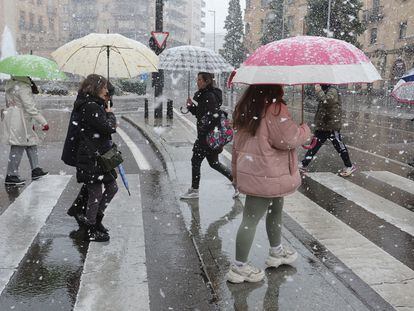 Varios peatones caminan en Salamanca bajo la nieve, este jueves.