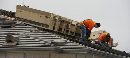 Trabajadores instalan paneles solares en una casa en construcci&oacute;n.