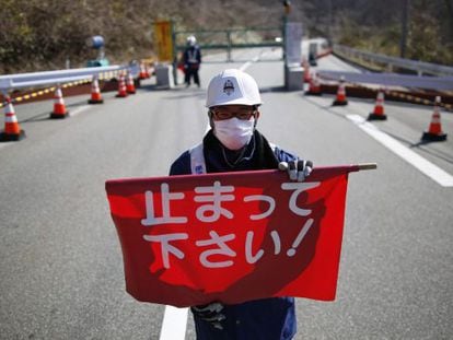 Un guarda de seguridad sostiene una bandera que dice "¡Pare!" en un puesto de control de Fukushima.
