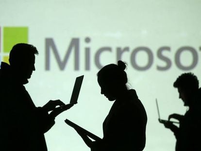 Usuarios con sus portátiles delante del logo de Microsoft