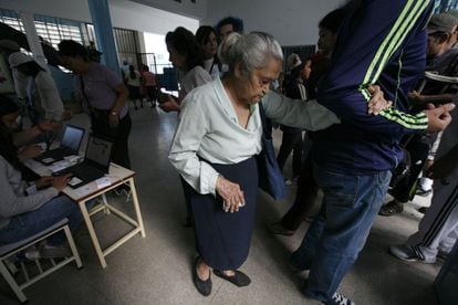Una votante es ayudada a llegar hasta la urna en el barrio de Petare, en Caracas.