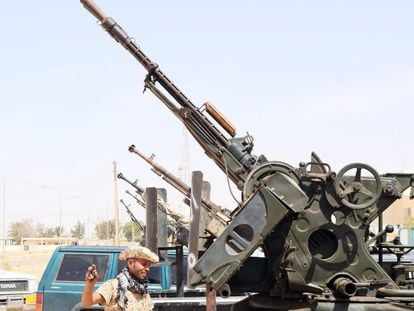 Un miembro de las milicias libias leales al Gobierno de Unidad, delante de varias armas situadas en el puesto de control de Ab&uacute; Grain, al este de Misrata, el 18 de mayo. 