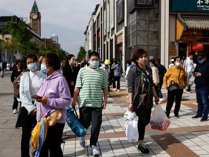 Personas caminando en una calle comercial de Pekín el pasado sábado.