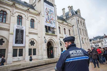 Un policía vigila el Ayuntamiento de Angulema, que exhibe un cartel de homenaje a 'Charlie Hebdo'.