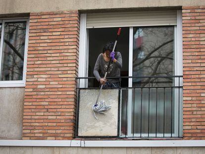 Una dona neteja l'exterior del seu balcó.