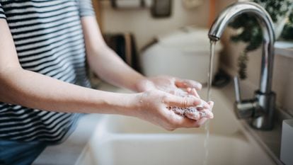 Una mujer se lava las manos con jabón en el fregadero.