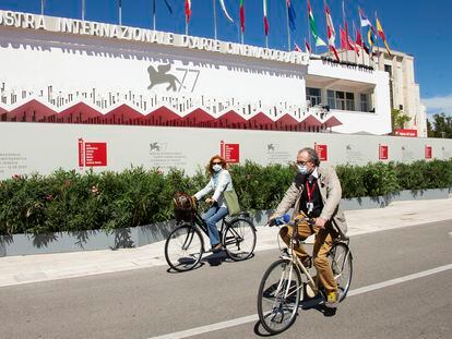 Asistentes al festival pasean en bicicleta frente al palacio del festival, este martes en Venecia.