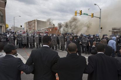 Un grupo de manifestantes unidos forman una cadena frente al cordón policial que bloquea una calle durante las protestas en Baltimore.