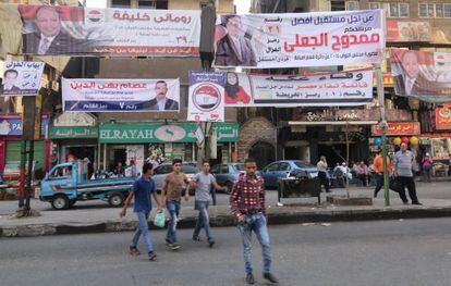Varias personas caminan junto a pancartas electorales en Giza.