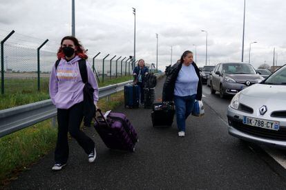 Pasajeras caminan por la carretera con sus maletas durante la jornada de huelga en la Terminal 1 del aeropuerto de París-Charles de Gaulle, este jueves. 