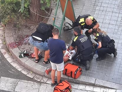 Agentes de la Guardia Urbana de Barcelona atienden a un herido tras la pelea con catanas en el barrio de Gràcia de la ciudad, el viernes.