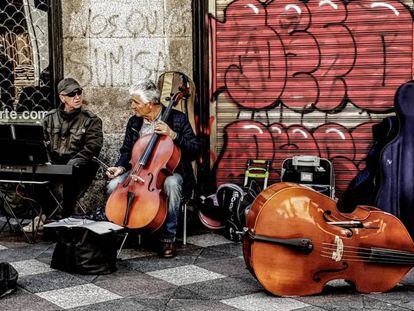 Dos músicos tocan al final de la calle del Arenal, junto a la plaza de Ópera.