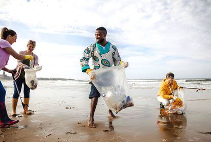 Varias personas recogen botellas y recipientes de plástico en una playa de Reino Unido.