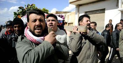 Varios hombres portan un cad&aacute;ver en Qusayr, cerca de Homs.