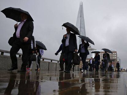 Trabajadores londinenses bajo la lluvia, este lunes.