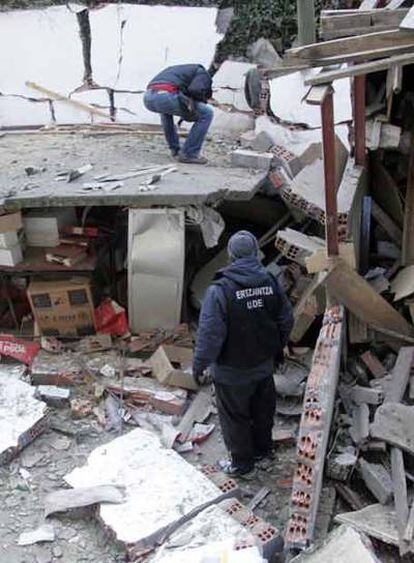 Varios <i>ertzainas</i> examinan los daños del ataque contra la sede del PSE en Balmaseda (Vizcaya).