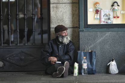 Un mendigo, un hombre mayor, pide limosna en los soportales de la plaza Mayor de Madrid.