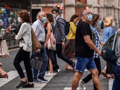 Varias personas pasean por las calles de Bilbao protegidas con mascarillas.