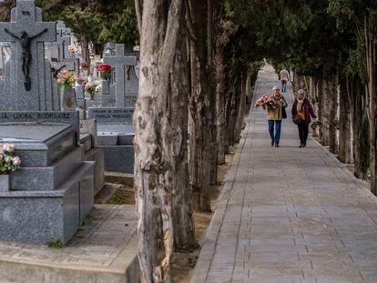 Dos mujeres conversan mientras se dirigen a dejar flores en la tumba de algún ser querido en el cementerio de Toledo.