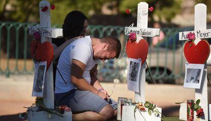 Amigos de una de las víctimas de la matanza de Las Vegas, junto a una cruz en su honor.