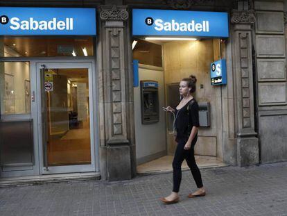 Una dona passa per una oficina de Banc Sabadell, a Barcelona.