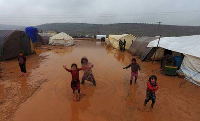Niños sirios junto a las tiendas de un campamento de refugiados inundado, el domingo en Idlib.