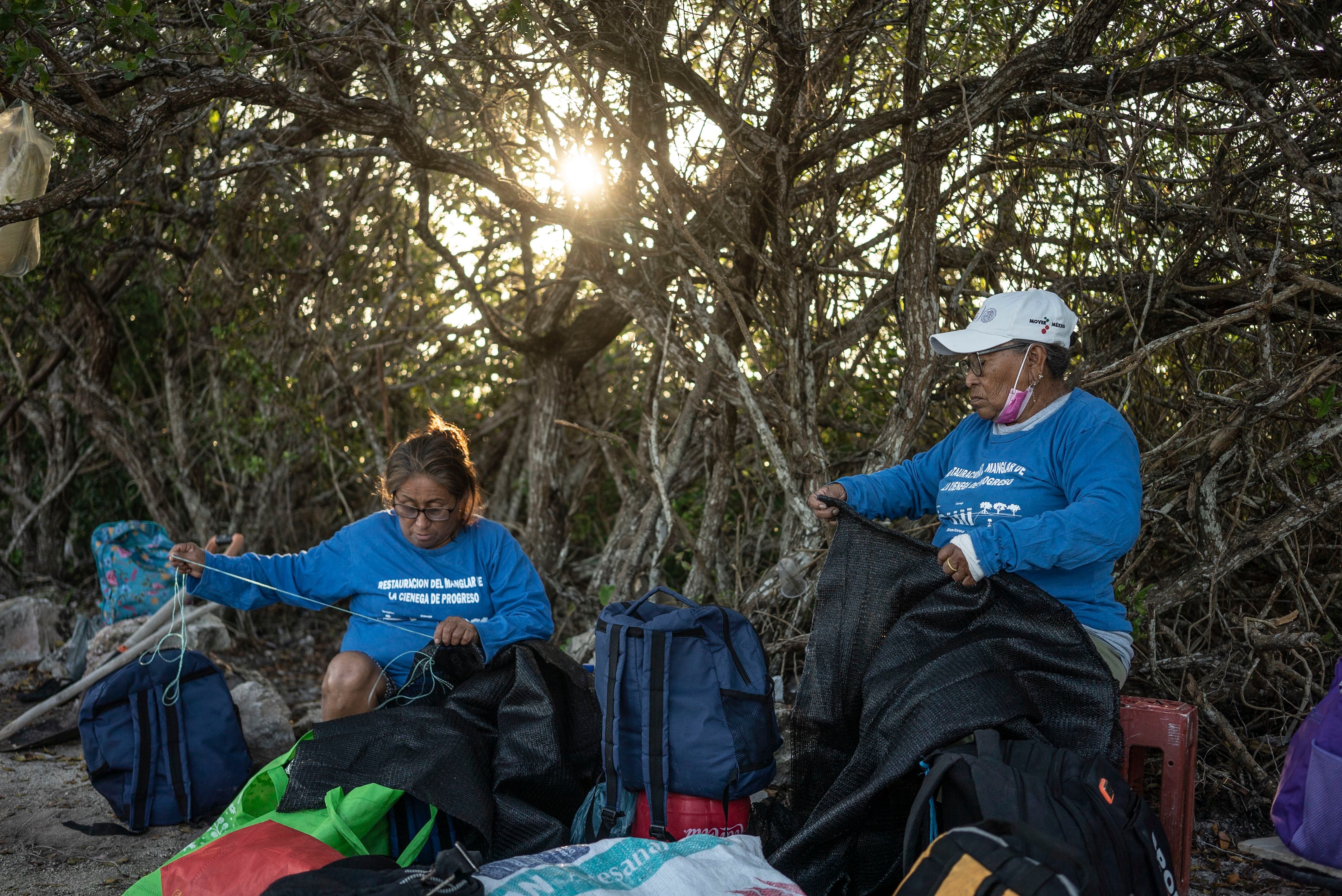 Italia Lira, de 63 años, y Antonia Pech, de 77, tejen las redes que usan las chelemeras en el proceso de regeneración de manglares en la costa de Progreso.