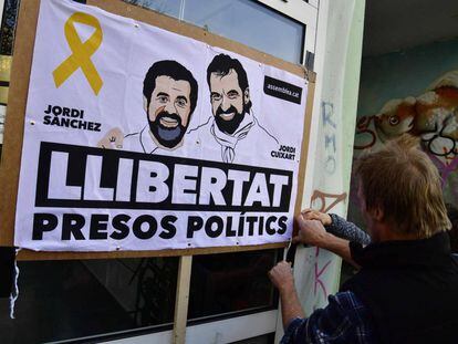 Un hombre coloca una pancarta con los rostros de Jordi Sànchez y Jordi Cuixart en Berlín el 7 de abril.