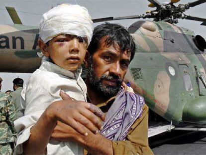 Un padre sostiene a su hijo en una base militar cercana a Islamabad tras ser evacuados de Muzaffarabad.