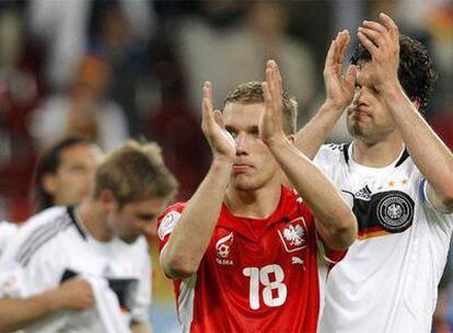 Podolski, con la camiseta roja de Polonia, aplaude junto a Ballack a la afición alemana.