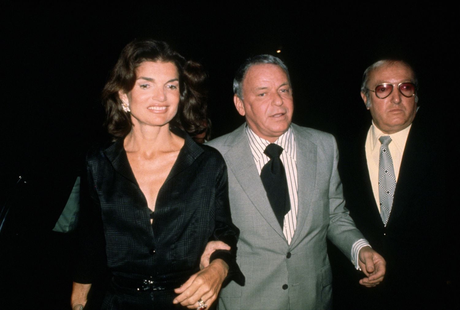 Jacqueline Kennedy Onassis, Frank Sinatra y el guardaespaldas Jilly Rizzo llegando al Club 21 en 1975 tras un concierto del cantante en Nueva York. 