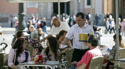 Un camarero sirve bebidas en una terraza en la plaza de la Virgen de Valencia.