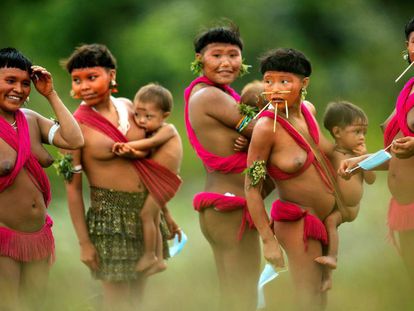Integrantes del pueblo yanomami sujetan mascarillas y cargan a sus bebés el 1 de julio de 2020 en la región de Surucucu, municipio de Alto Alegre, estado de Roraima (Brasil). El coronavirus ha llegado a la mayor tierra indígena de Brasil y amenaza a los históricos guardianes de la Amazonía.