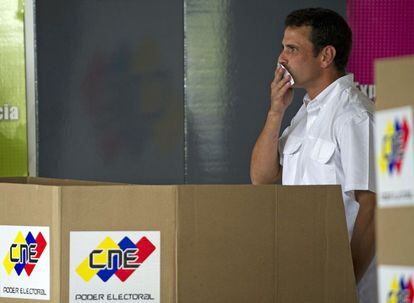 El candidato opositor Henrique Capriles besa su papeleta antes de votar este domingo en un colegio de Caracas.