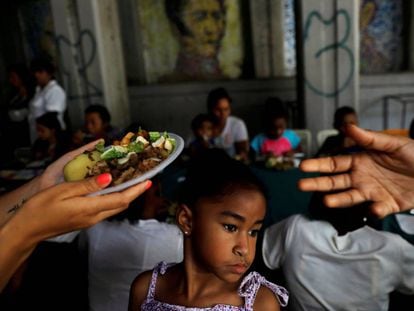 Un par de voluntarios reparten comida en Caracas, en mayo pasado. 