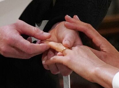 El príncipe Enrique coloca el anillo de boda a Meghan Markle.