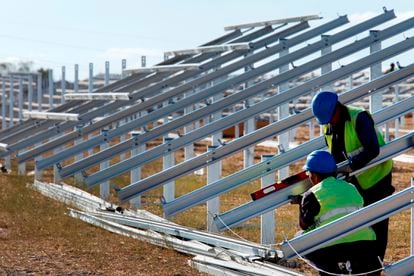 Two operators work on a new photovoltaic solar installation.