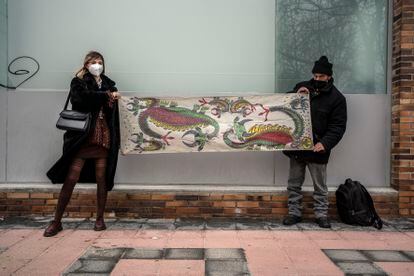 Carlota Ginzo y Alberto Torres sostienen una tela decorada con dragones en el barrio de Arganzuela en Madrid. 