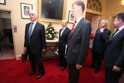 El ministro del Tesoro laborista, Alistair Darling (izquierda), sale de Downing Street, en Londres, antes de presentar los presupuestos.