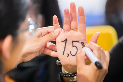 Activistas se pintan en las manos "1,5 grados", el objetivo del Acuerdo de París, en la cumbre de Clasgow.