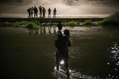Un hombre cruza el río Bravo, con un niño en brazos, para entregarse a la Patrulla Fronteriza en Texas.