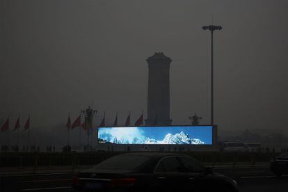 Una valla publicitaria con un paisaje luminoso y nevado, en la Plaza de Tiananmen, contrasta con el ambiente gris provocado por el exceso de polución en Pekín. La contaminación del aire ha causado un aumento en el número de personas que se acercan a los hospitales con problemas respiratorio.