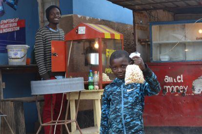 Gift James vende una bolsa de palomitas a un niño en Bauleni, Lusaka. Con las ganancias está financiado un equipo de fútbol.